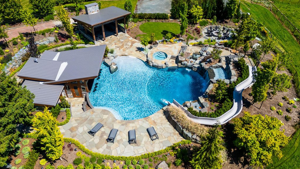 Overhead view of a freeform custom pool featuring a swim-up bar, rock accents, and surrounding luxury hardscaping.