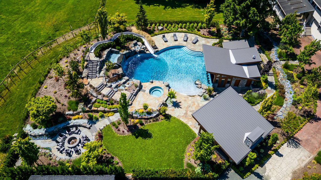 Full aerial layout of a custom property featuring a luxury pool, spa, patios, fire pit, and integrated landscape paths.