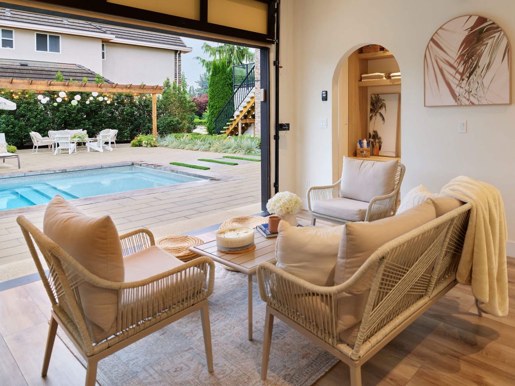 Modern indoor lounge area opening to a backyard pool and pergola.
