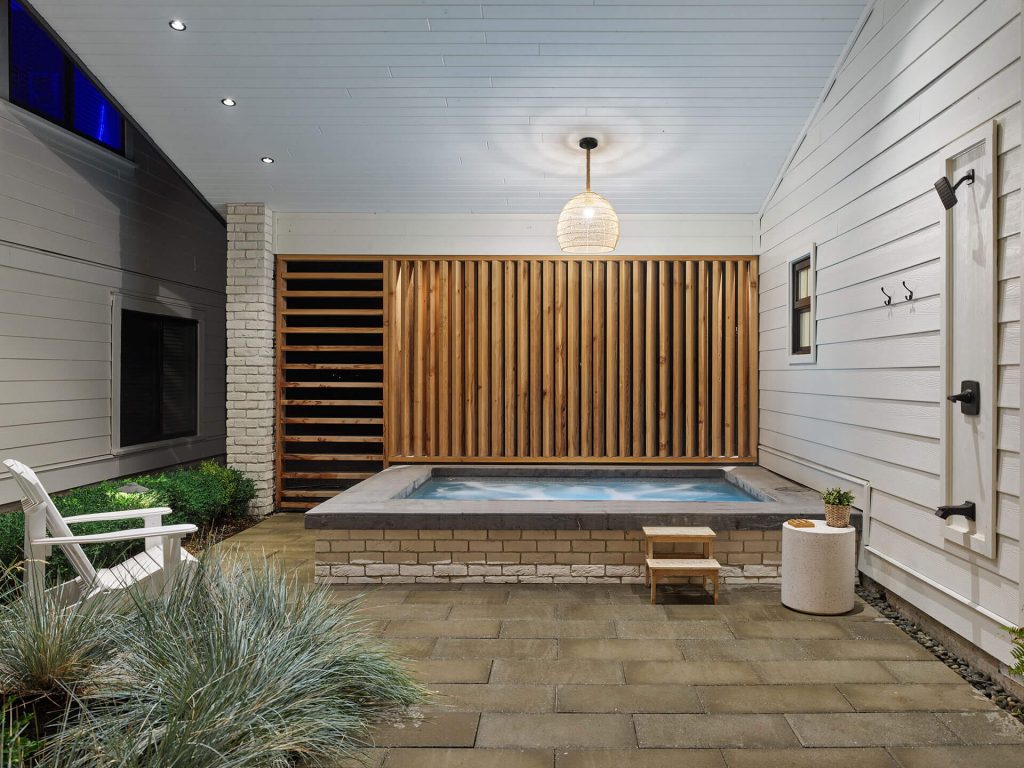 Enclosed spa courtyard featuring a hot tub and vertical wood privacy screen.