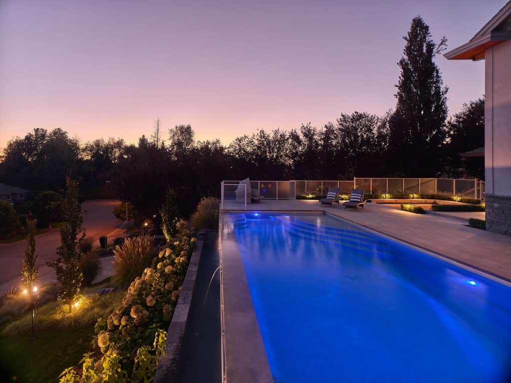 Raised infinity pool with illuminated water and panoramic sunset views.