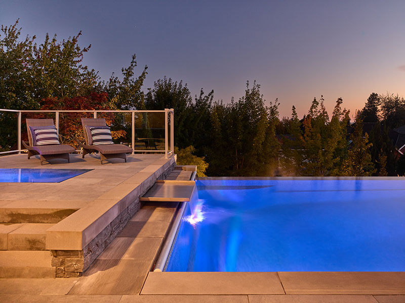 Luxury custom pool with natural rock waterfall, and integrated water features designed by Rockwest Creative.