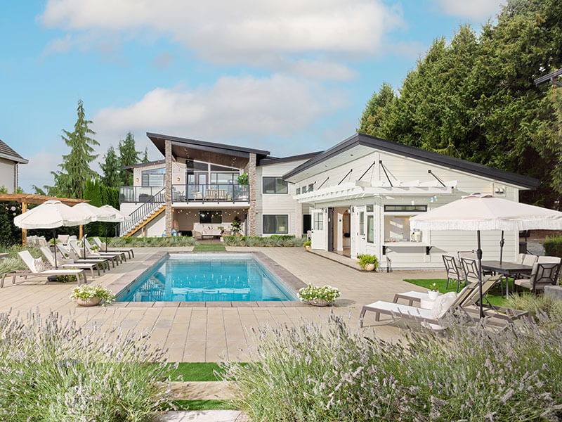 Luxury outdoor living space with custom rectangular pool, lounge areas, and modern home design crafted by Rockwest Creative.