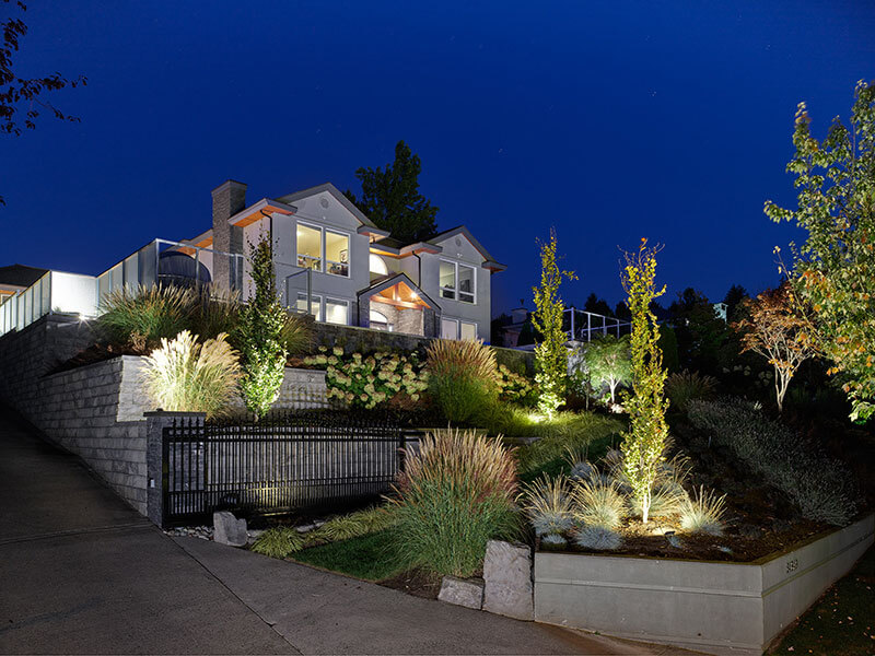 Professional landscape lighting illuminating terraced planting beds and architectural features designed by Rockwest Creative.