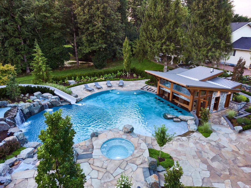 Luxury custom pool with modern pool house, lounging areas, and elegant outdoor living by Rockwest Creative.