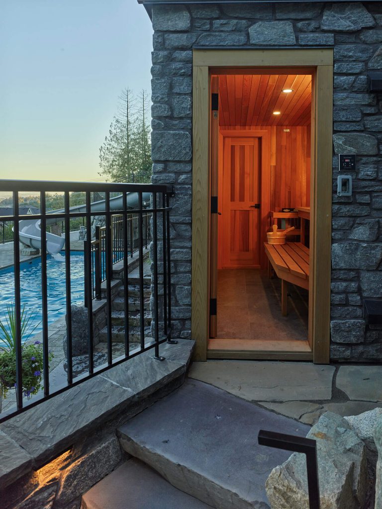 Outdoor sauna with stone entry steps overlooking the pool and waterslide.