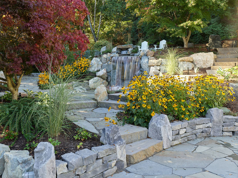 Layered planting design with perennials, grasses, and stone terraces enhancing a custom landscape created by Rockwest Creative.