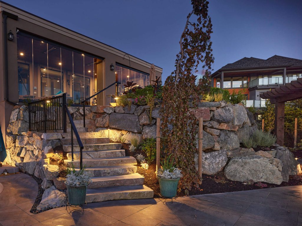A dramatic stone staircase set into a terraced boulder wall, accented with warm architectural lighting.